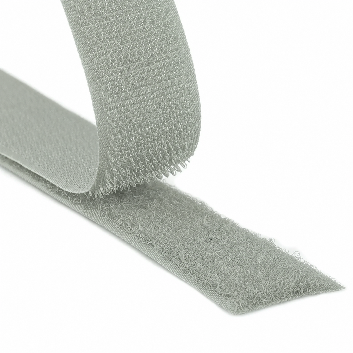 Close-up of a light grey hook and loop fastener tape showing both hook and loop sides on a white background